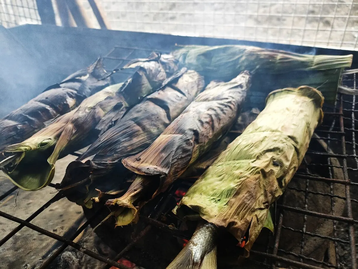 Grilled stuffed milkfish with charred skin, tomatoes and onions on a banana leaf