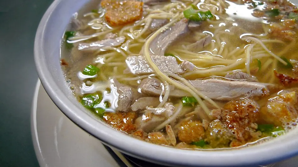 Bowl of La Paz batchoy with egg noodles, sliced pork, liver, crushed chicharon and spring onions