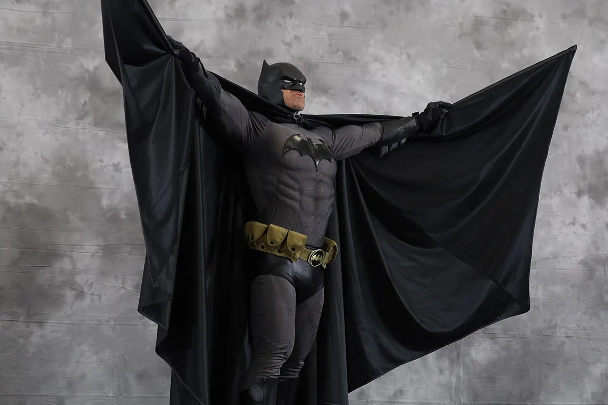 Batman cowl and cape silhouette against a dark city skyline at night