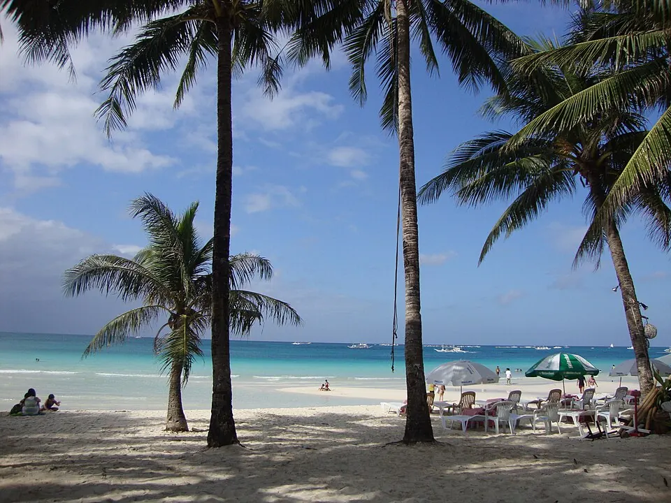 White Beach in Boracay with sailboats on turquoise water and palm trees along the shore