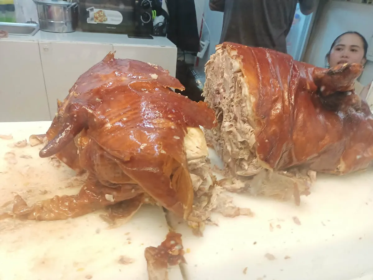 Rolled Cebu-style lechon belly with crackling golden skin sliced on a wooden board
