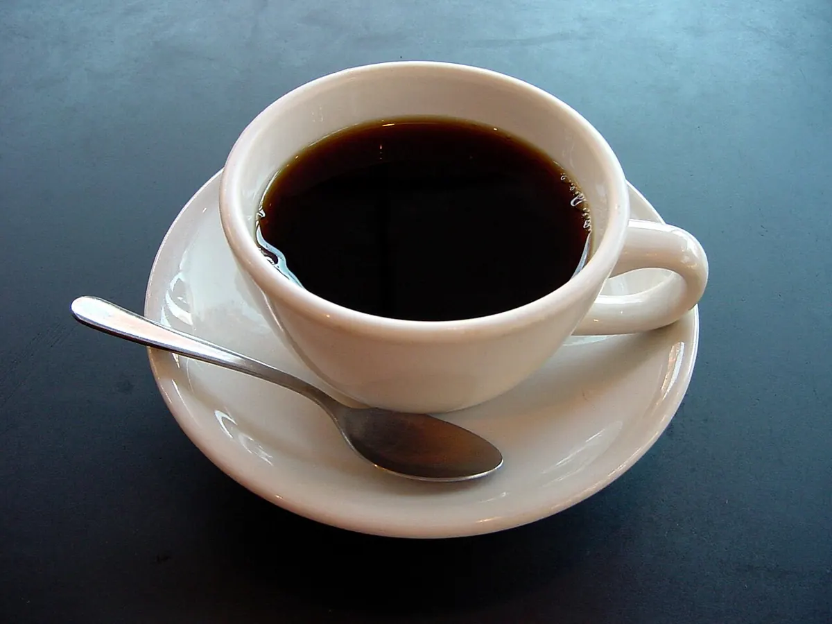 Barista pouring latte art into a cup of locally grown coffee at a cafe counter