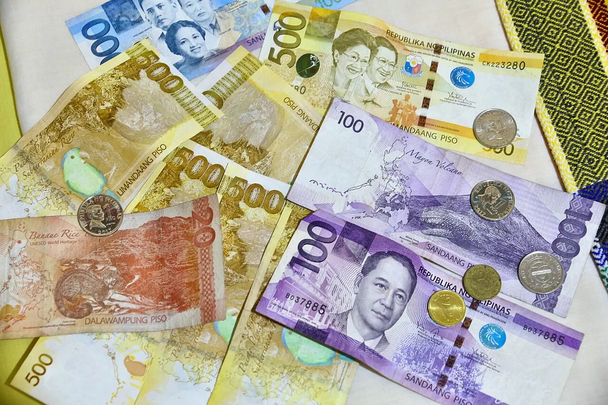 Philippine peso bills and a notebook used to plan a monthly budget in Cebu or Davao