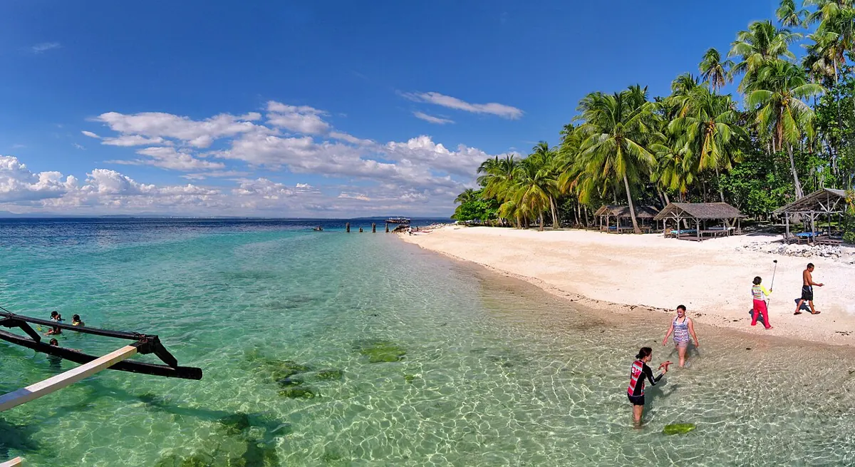 White sand beach with clear turquoise water and coconut trees on Samal Island near Davao City
