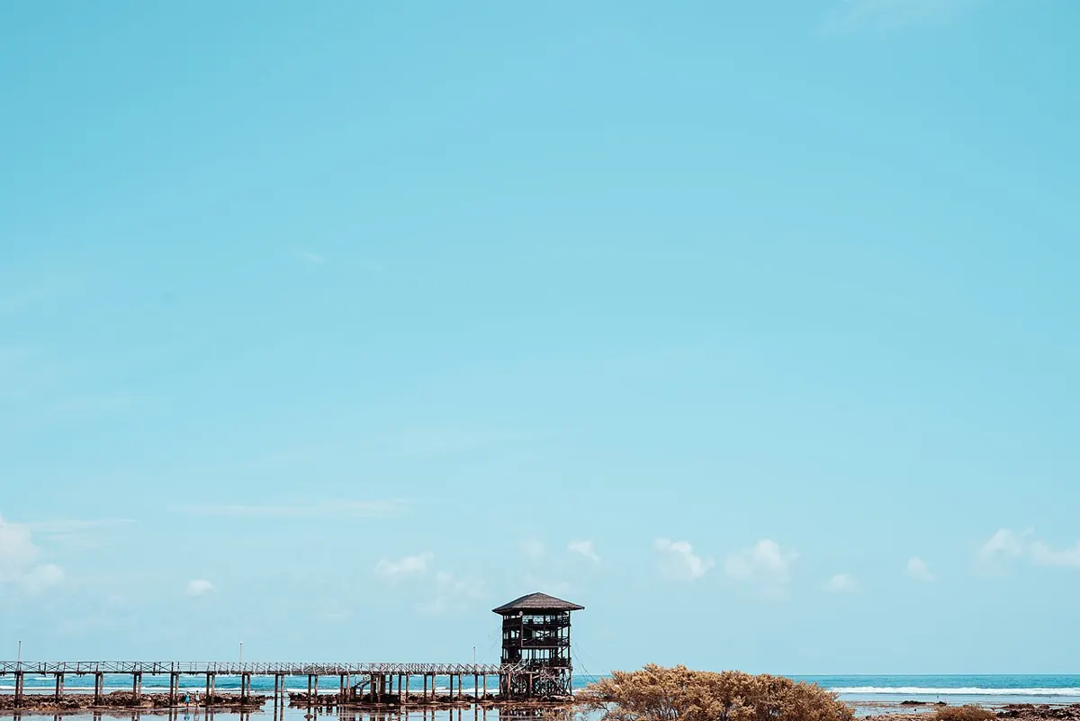 Surfers paddling out at Cloud 9 in Siargao beside the wooden boardwalk